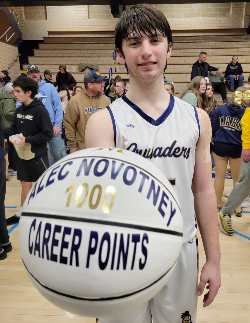 Marquette junior Alec Novotney displays the basketball commemorating his 1,000th career point in Friday's 60-40 win over Henry-Senachwine in Bader Gym in Ottawa.